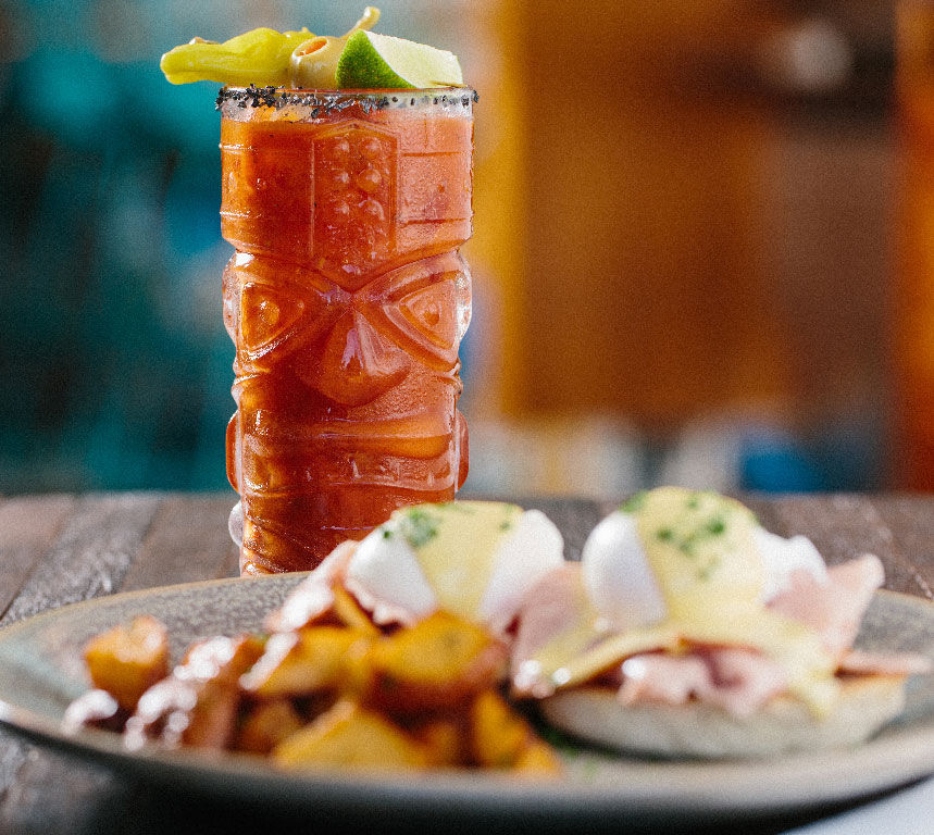 photo of a breakfast plate of eggs and potatos with a cocktail